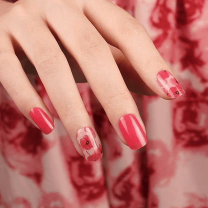 Hand wearing pink poppy nail wraps with coral accent nails manicure