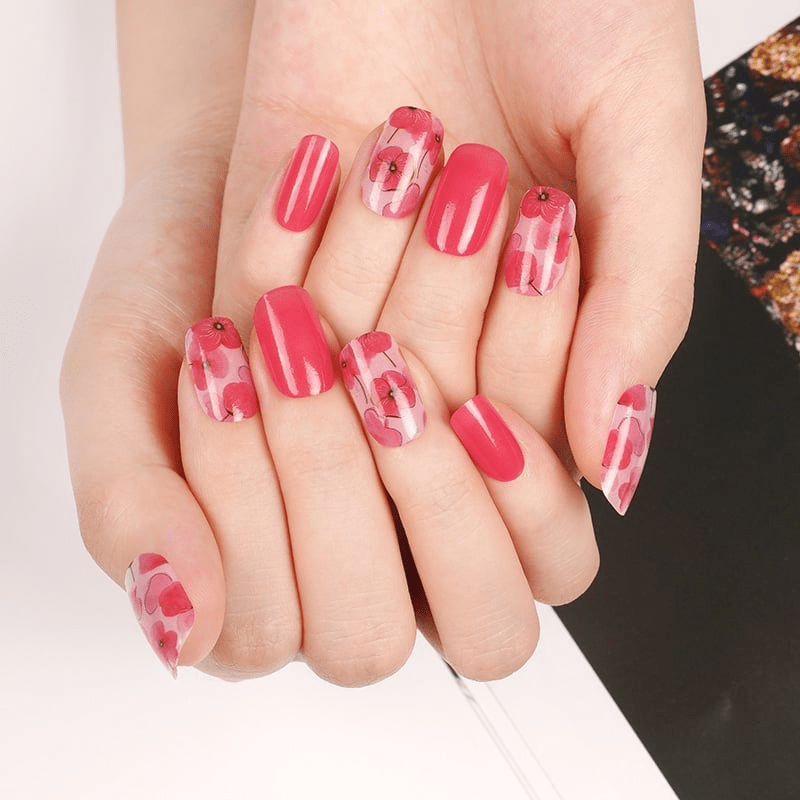Hands displaying pink watercolour poppy nail art wraps floral manicure design