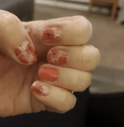 Coral pink poppy floral nail wraps on hand showing watercolour flower design