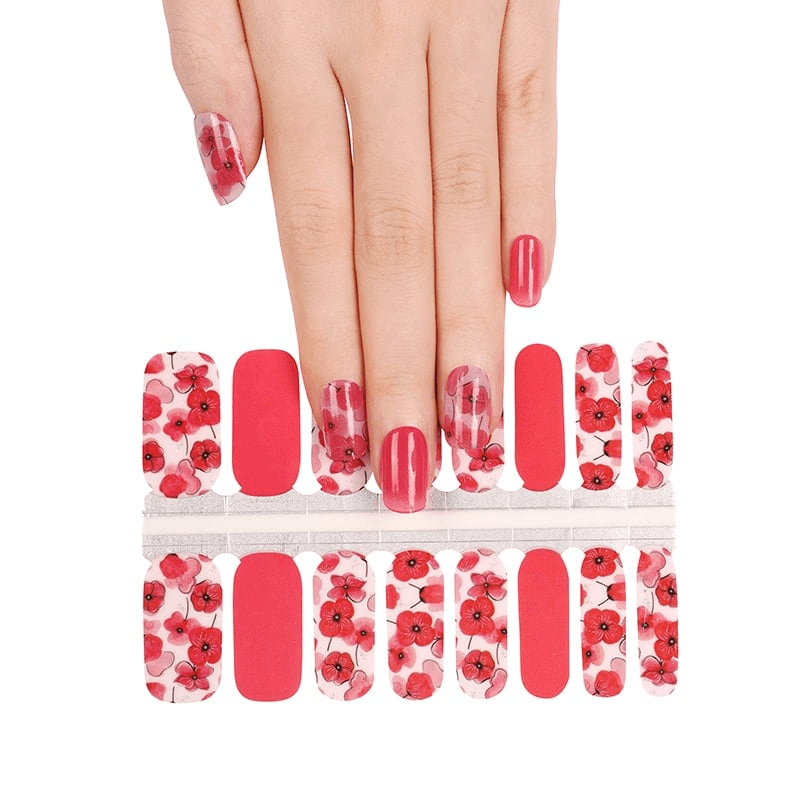 Hand reaching for red poppy nail wraps sheet showing floral nail art design