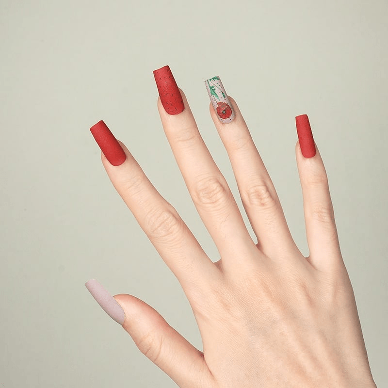 Red matte nail wraps with poppy flower design on hand showing at-home manicure