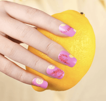 Hand on orange showing pink nail art with prawn cocktail themed nail wraps