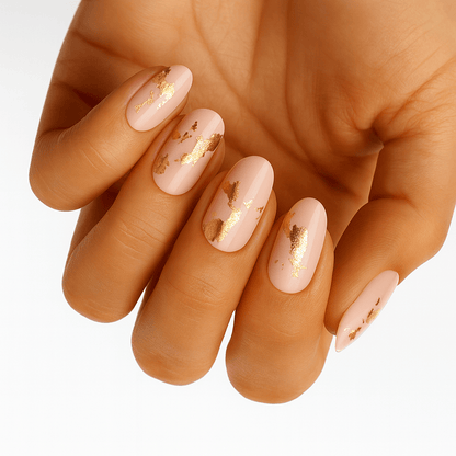 Nude nail wraps with gold foil flake accents on almond-shaped nails
