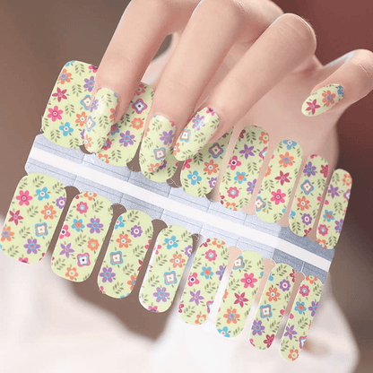 Colourful floral nail wraps on hand featuring tiny spring flowers on cream background