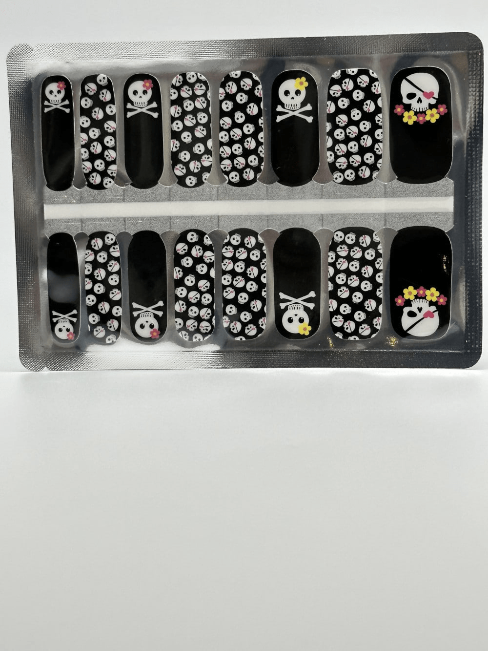 Gothic skull pattern nail wraps sheet showing black base with white skulls and crossbones design