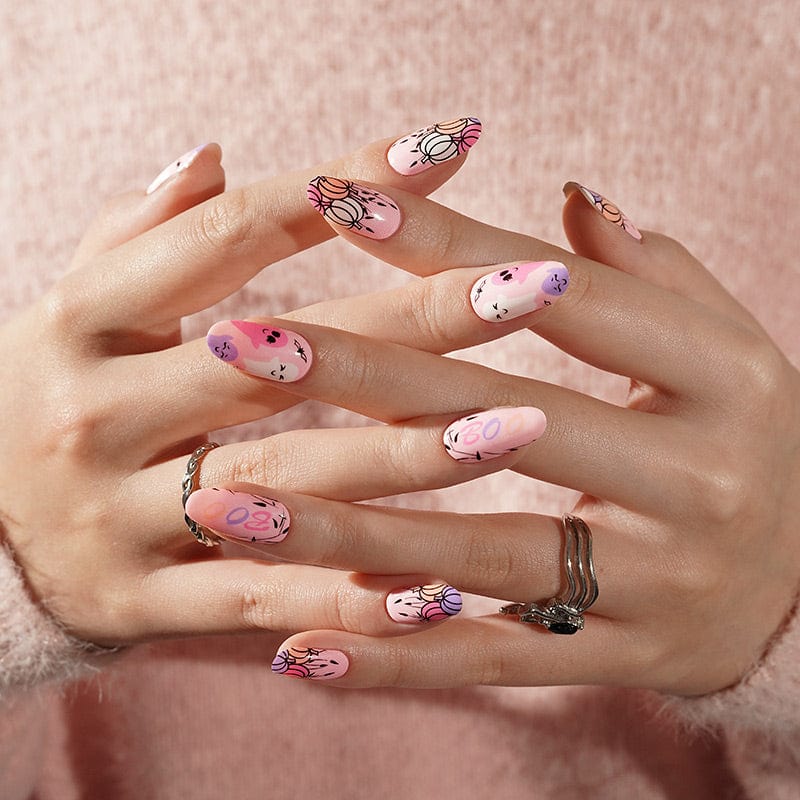 Clasped hands displaying pink Halloween nail wraps with adorable spooky characters