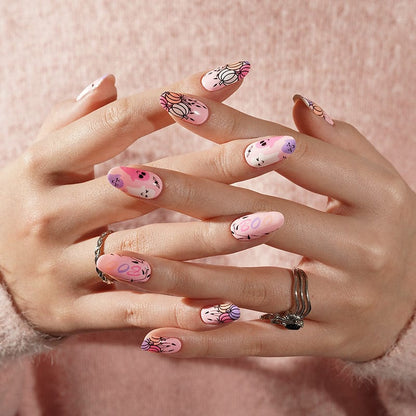 Clasped hands displaying pink Halloween nail wraps with adorable spooky characters