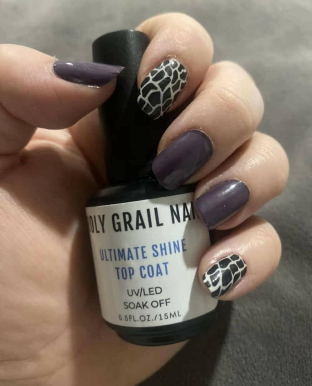 Purple manicure with black white python print nail wraps and top coat bottle