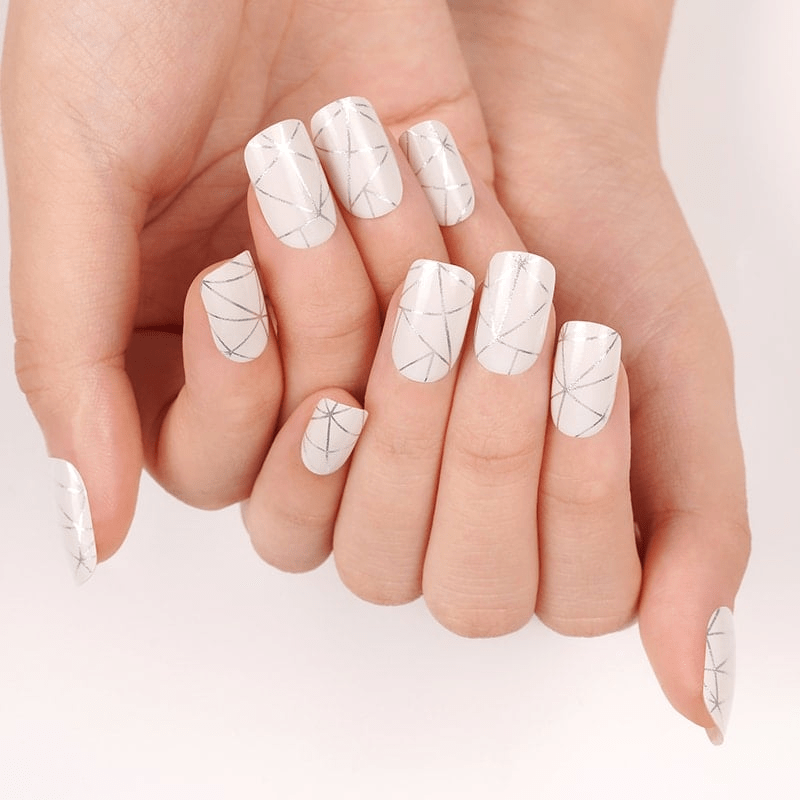 Manicured hands showing silver geometric nail wraps with mirror chrome and angular patterns