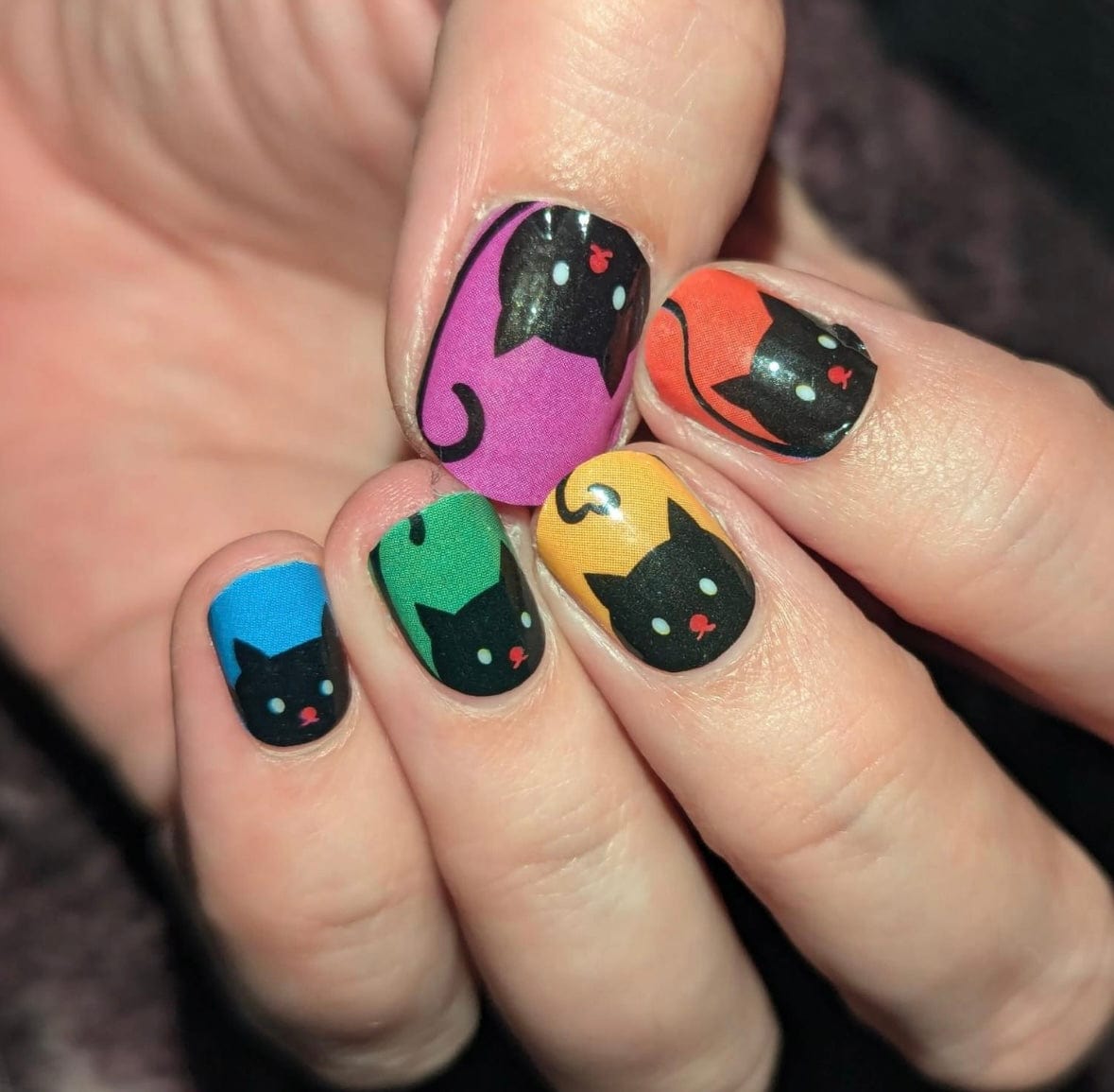Kawaii cat nail art wraps showing black cats with rainbow coloured tails on hand