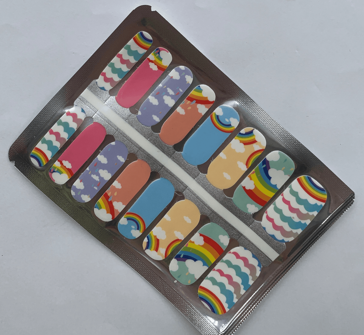 Non-UV nail wraps sheet featuring rainbow clouds and whimsical pastel nail art designs