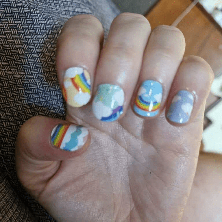 Hand wearing rainbow cloud nail art wraps in pastel colours and multicolour patterns