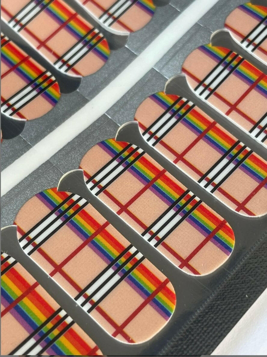 Close-up of rainbow plaid nail wraps showing beige base with colourful striped pattern