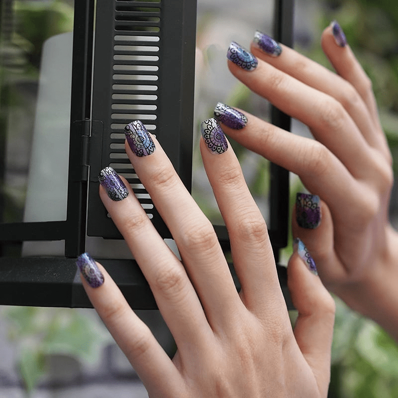 Hands showcasing iridescent ombre nail wraps with ornate lace design patterns