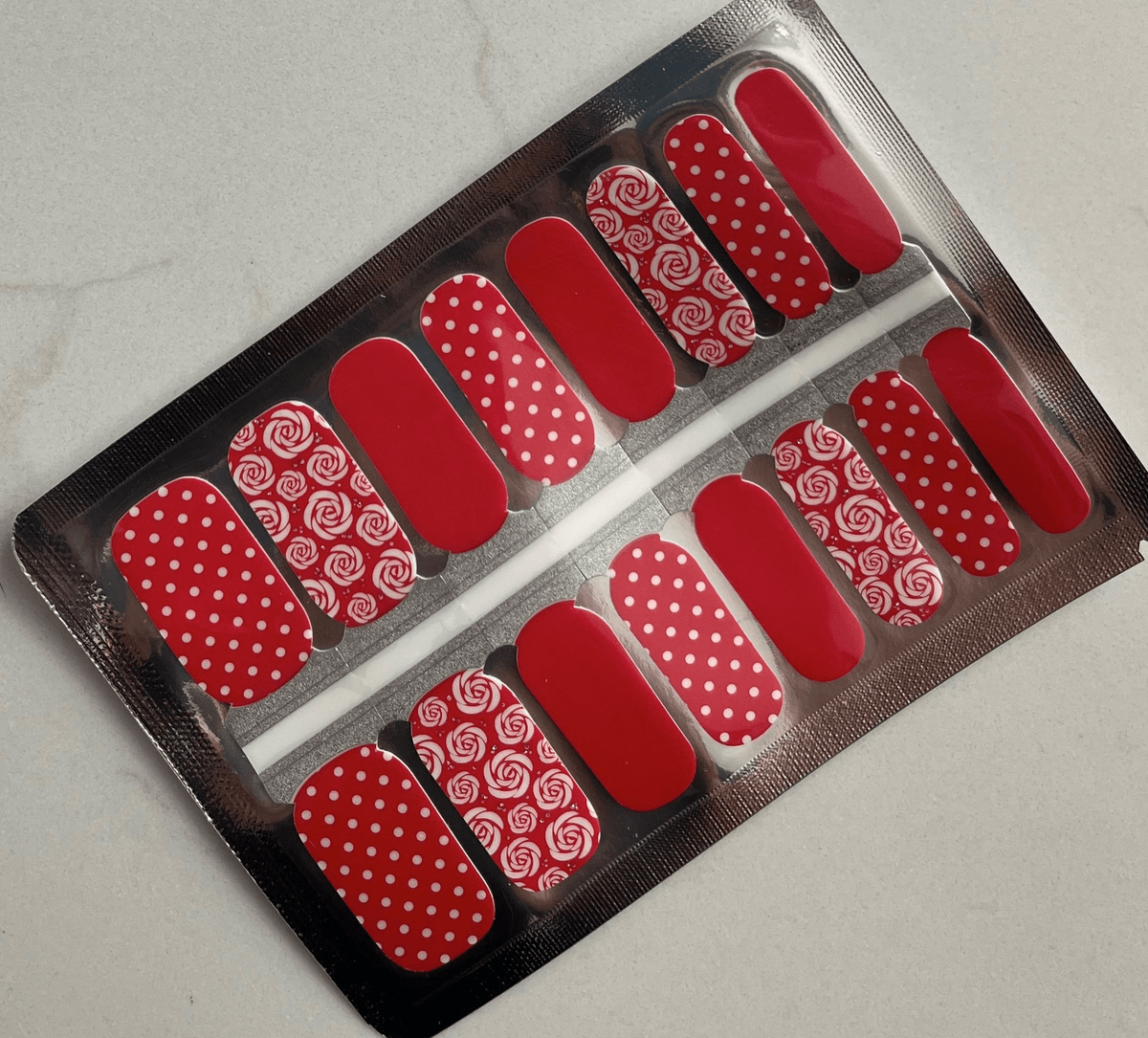 Red nail wraps sheet with white roses and polka dot patterns for at-home manicure