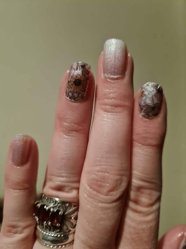 Hand wearing floral nail wraps with pink ombre and botanical pattern manicure