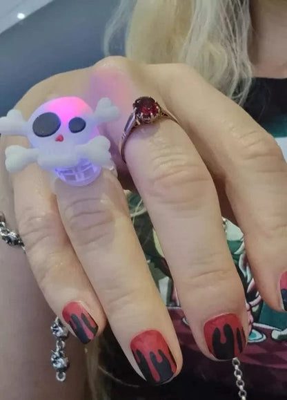 Hand showing black red flame nail art wraps with skull decoration
