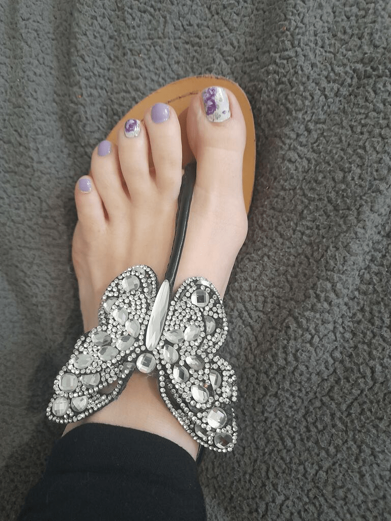 Lavender floral toe nail wraps on feet wearing ornate beaded sandals for summer