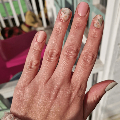 Hand displaying vintage rose garden nail art wraps with soft pink botanical design