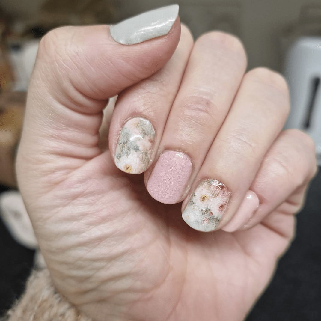 Hand wearing soft pink nail wraps with delicate watercolour rose floral patterns