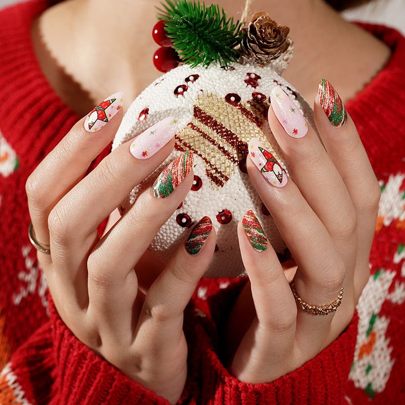 Hands holding Christmas ornament wearing festive nail wraps with Santa and candy cane stripe nail art