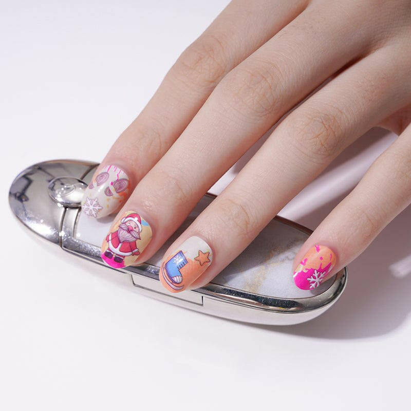 Hand wearing festive Christmas nail wraps featuring Santa, reindeer and holiday cartoon designs on pink and blue background