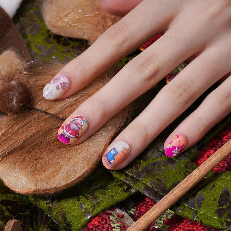 Hand wearing bright multicoloured Christmas nail wraps with Santa cartoon designs on wooden surface