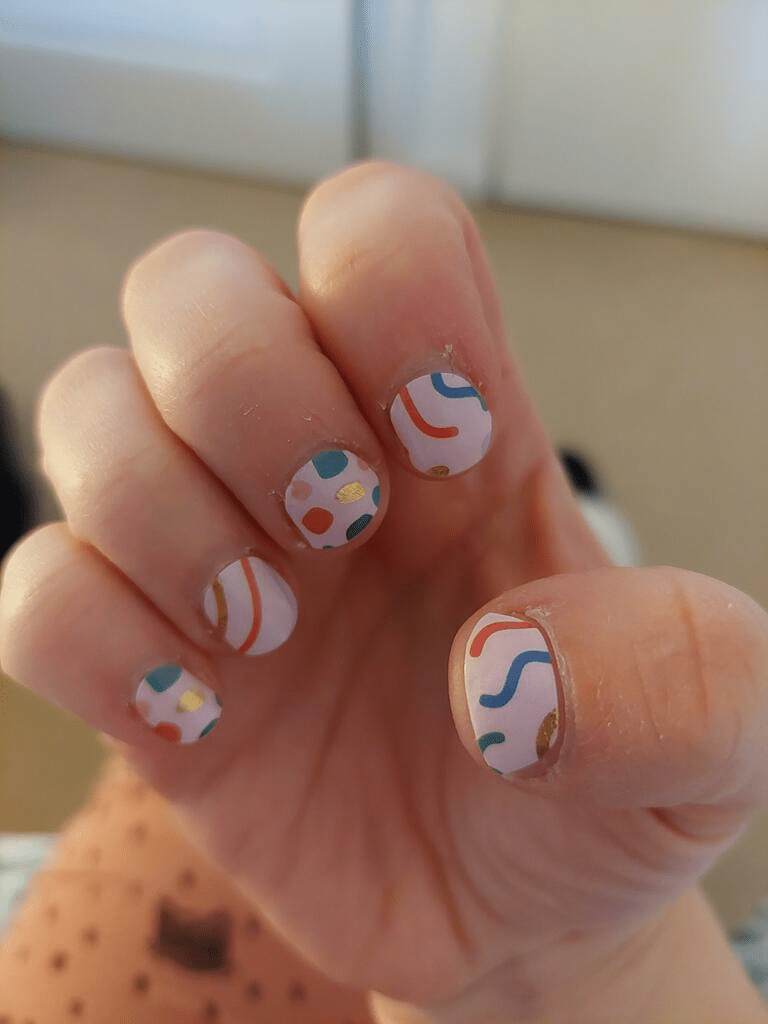 Retro abstract nail art wraps on fingers featuring multicoloured geometric Memphis design