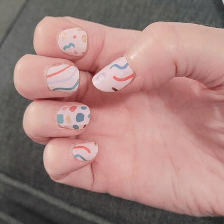 Colourful geometric nail wraps on hand featuring retro Memphis pattern in pink blue green