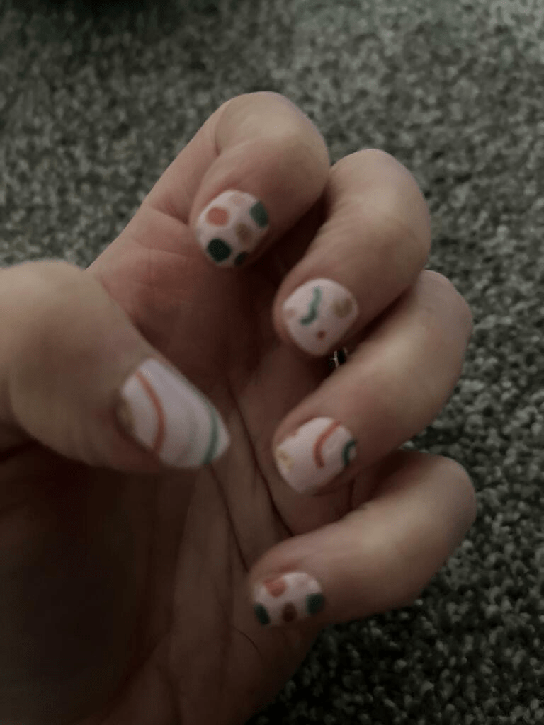Abstract geometric nail art wraps on hand with vintage 80s Memphis design multicolour pattern
