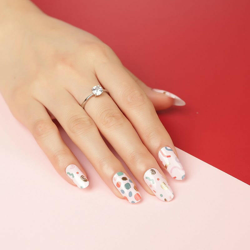 Hand wearing retro geometric nail wraps with multicoloured Memphis pattern manicure design