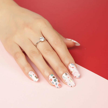 Hand wearing retro geometric nail wraps with multicoloured Memphis pattern manicure design