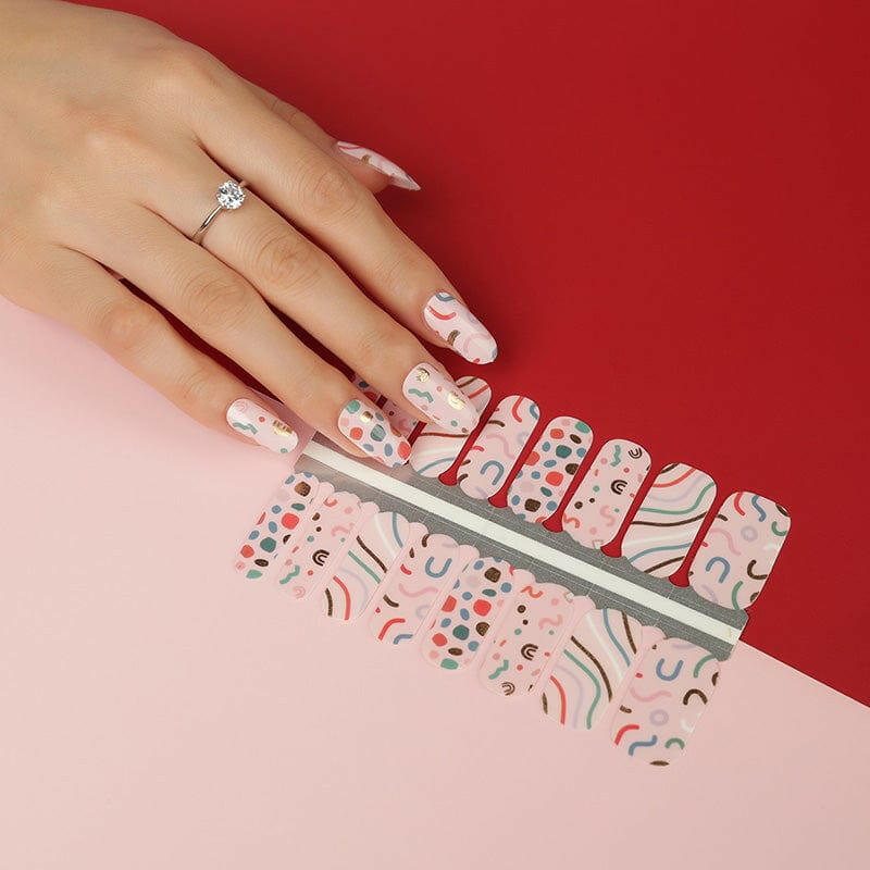 Colourful geometric nail wraps on hand with 80s Memphis pattern in pink blue yellow