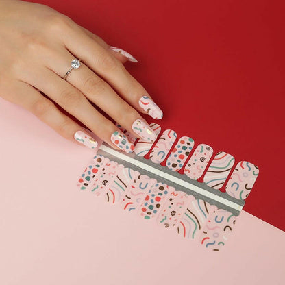 Colourful geometric nail wraps on hand with 80s Memphis pattern in pink blue yellow