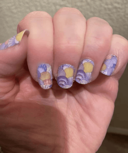 Purple watercolour seashell nail wraps with yellow details on hand manicure