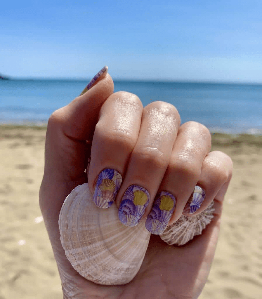 Holy Classics nail wraps in purple and gold glossy seashell print on short round nails