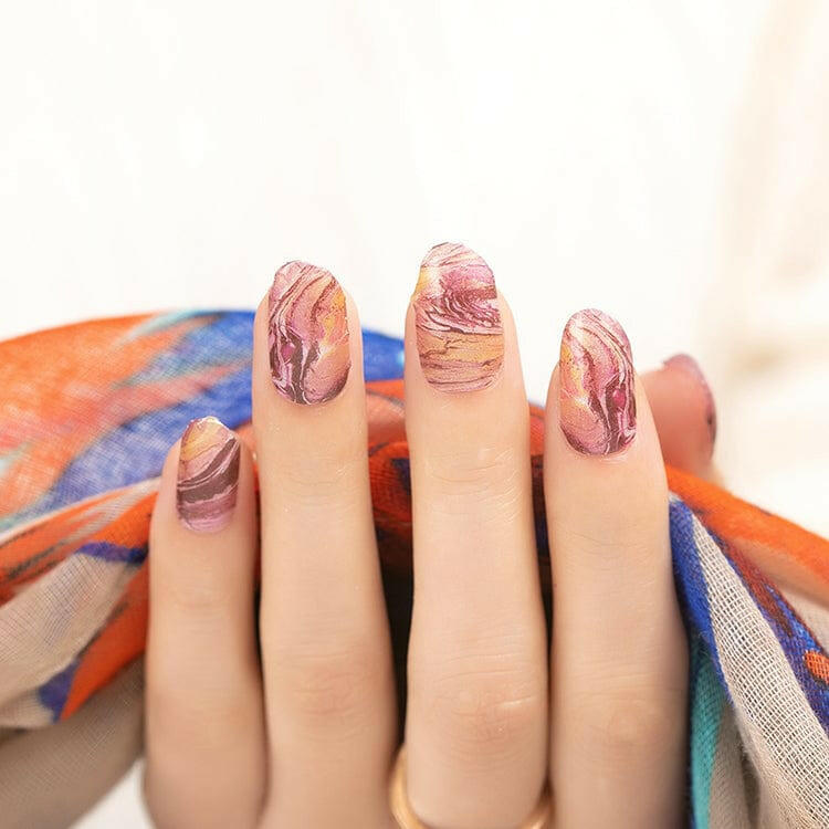 Hand displaying burgundy marble nail wraps with gold veining and stone-like texture