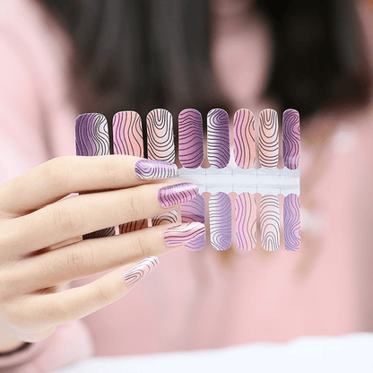 Hand wearing purple pink nail wraps with abstract wavy stripe nail art design