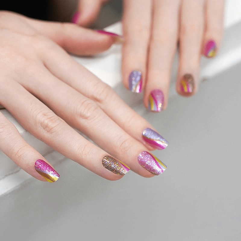 Woman's hands showcasing colourful glitter nail wraps with metallic pink yellow stripe designs