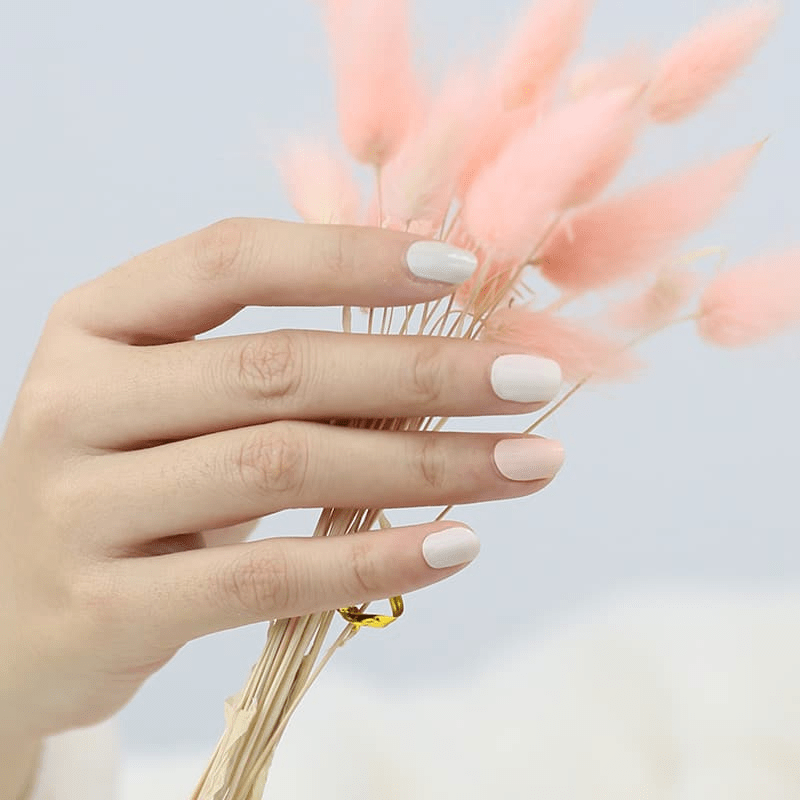 Hands holding dried wheat showing pastel sage green and pink non-UV nail wraps