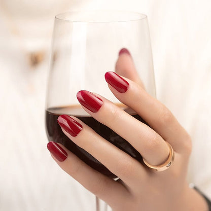 Glossy wine-red nail wraps, wide fit, shown on rounded nails holding a wine glass.