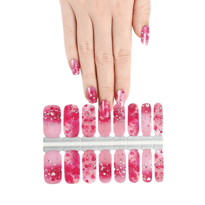 Pink ombre nail wraps with white hearts and glitter shown with applied nails