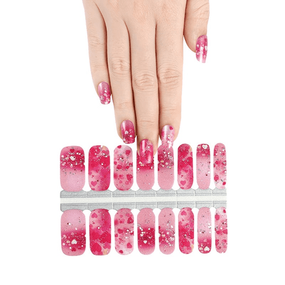 Pink ombre nail wraps with white hearts and glitter shown with applied nails