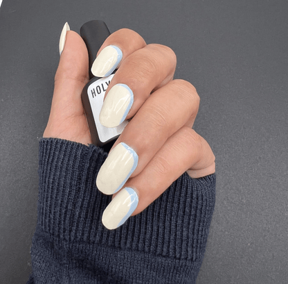 Blue French tip nail wraps on hand wearing navy jumper minimalist manicure style