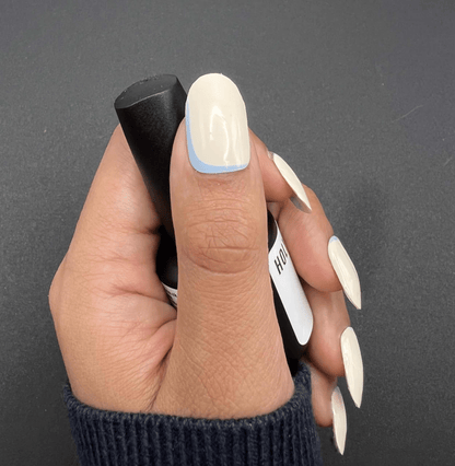 Hand holding blue French tip nail wraps showing elegant at-home manicure design