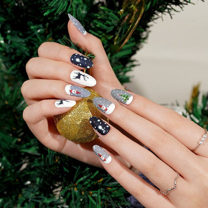 Christmas themed nail wraps on hand featuring navy snowflakes, white reindeer and festive holiday patterns