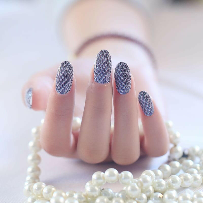 Grey snakeskin pattern nail wraps on hand with realistic reptile texture for statement manicure