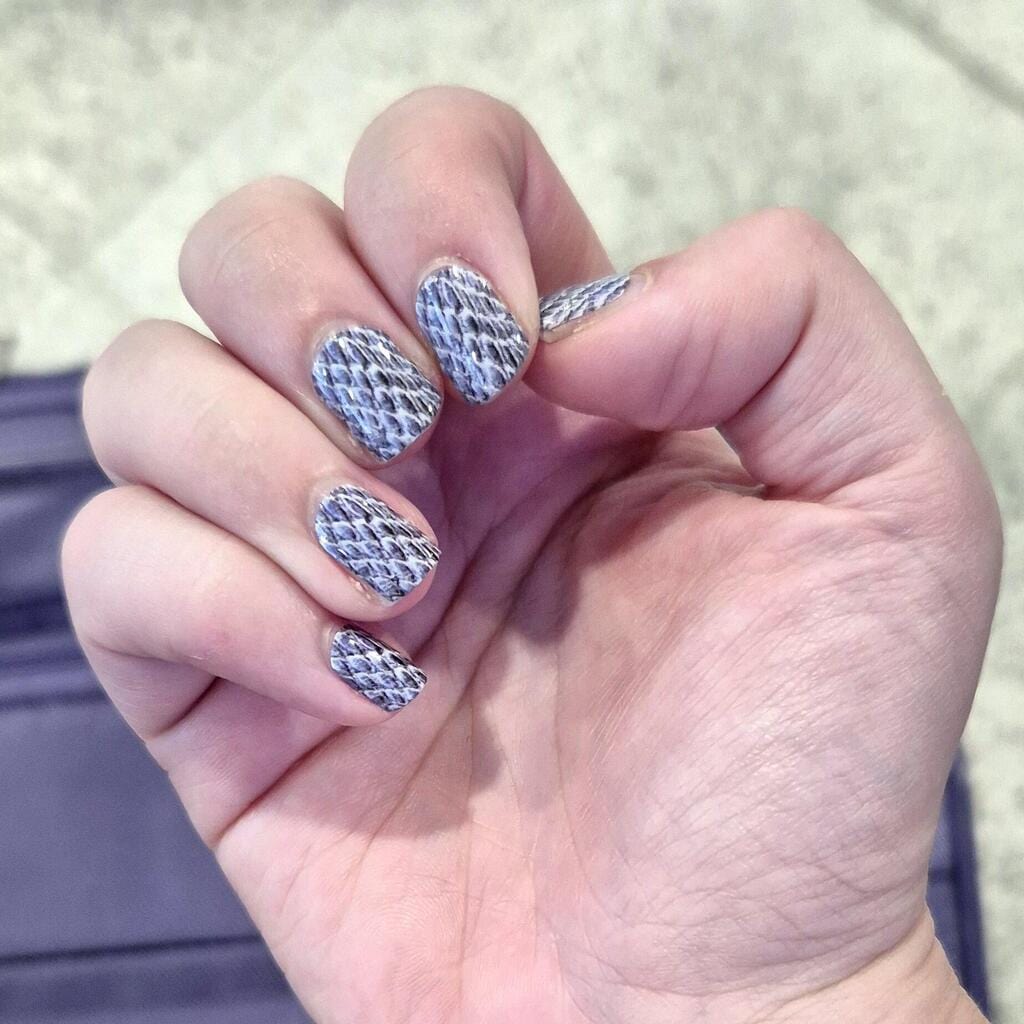 Monochrome snakeskin nail wraps on hand displaying grey reptile print design