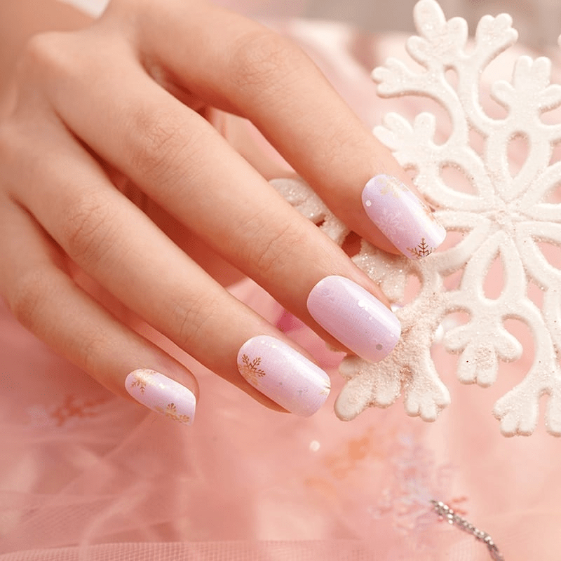 Close-up of hands showing pink nail wraps with subtle snowflake details for winter nails