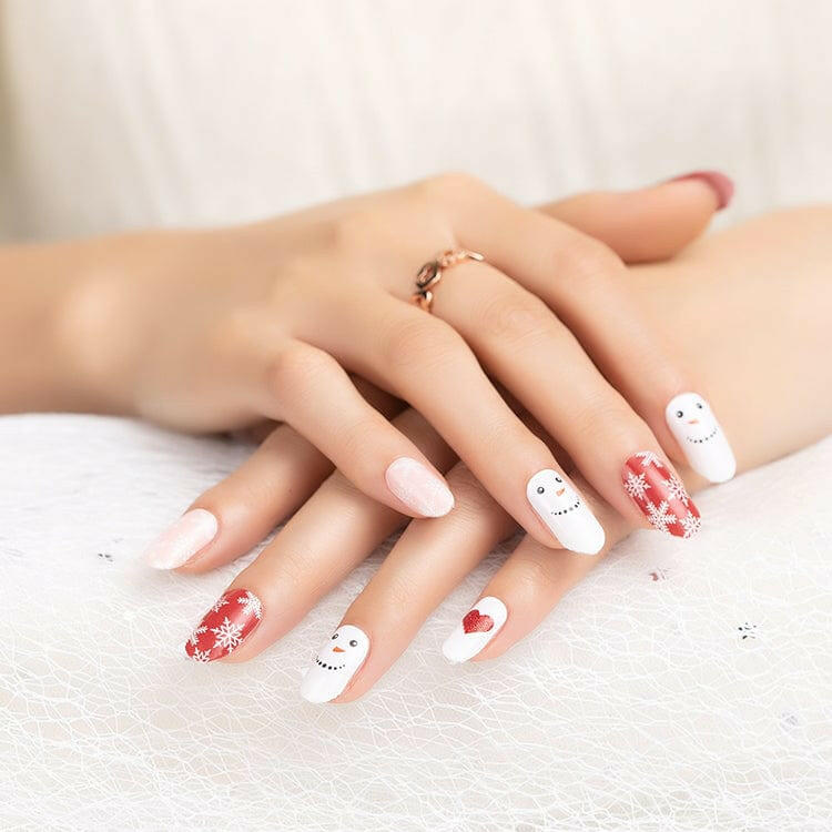 White Christmas nail wraps featuring cute snowman characters with red hearts on manicured hands